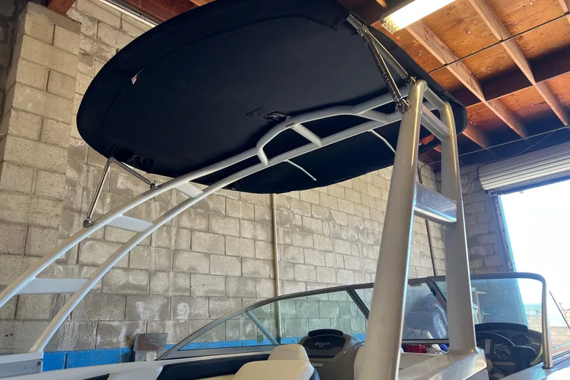 Slide: The Image of 2017 Chaparral 19 H2O Sport boat with bimini top in a garage setting. - 17