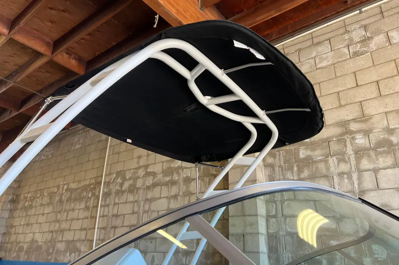 Slide: The Image of 2017 Chaparral 19 H2O Sport boat with black bimini top in a garage. - 18