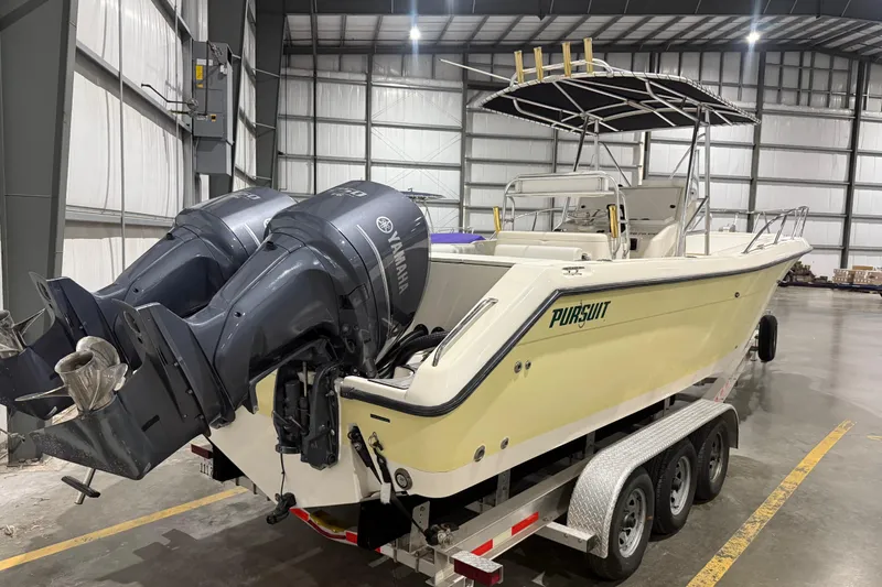 Slide: The Image of 1999 Pursuit 2870 Center Console boat with dual Yamaha engines in a warehouse. - 2