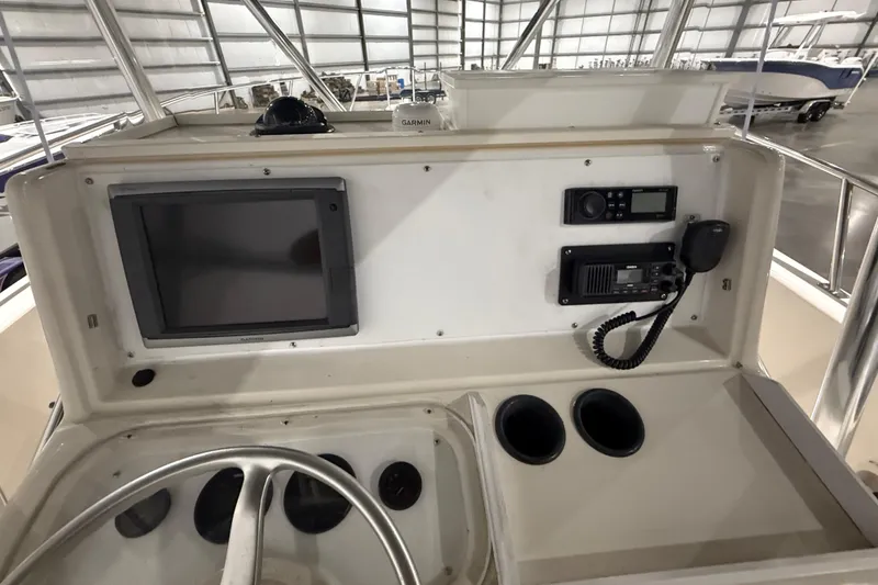 Slide: The Image of 1999 Pursuit 2870 Center Console boat in indoor storage, showcasing helm and seating area. - 24