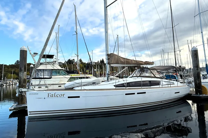 The Image of 2013 Jeanneau Sun Odyssey 44 DS sailboat docked at a marina under a cloudy sky. - 0