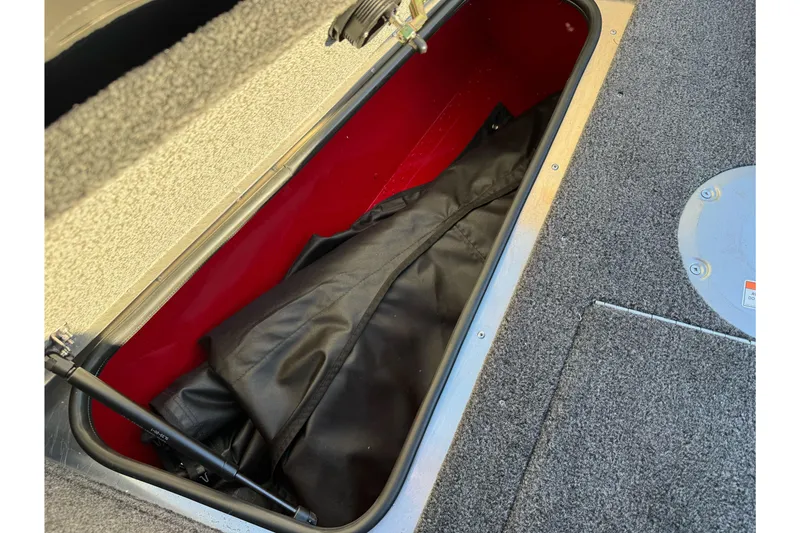 Slide: The Image of Storage compartment in 2026 Lund 1775 Adventure Sport boat, featuring carpeted interior and black cover. - 10