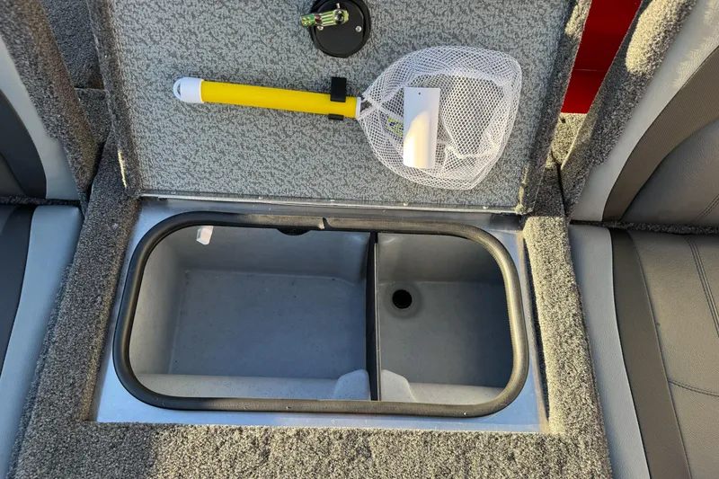 Slide: The Image of 2026 Lund 1775 Adventure Sport boat storage compartment with fishing net and yellow handle tool. - 13