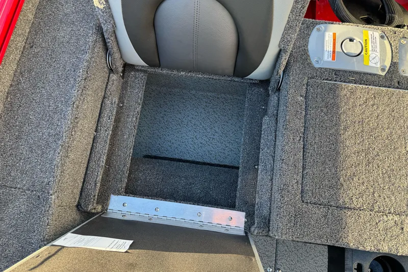 Slide: The Image of 2026 Lund 1775 Adventure Sport boat interior storage compartment with gray carpet and seat. - 14