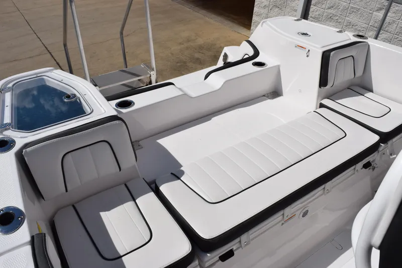 Slide: The Image of 2026 Yamaha Boats 255 FSH Sport H interior with white cushioned seating and cup holders. - 11