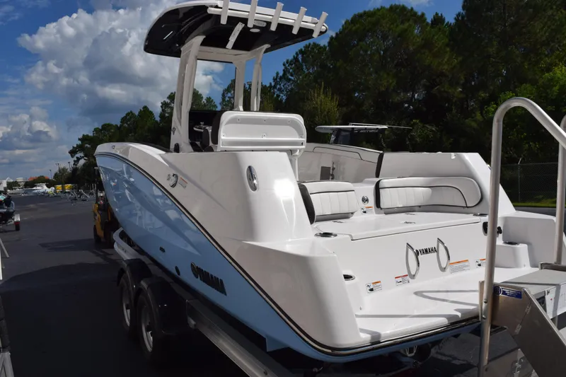 Slide: The Image of 2026 Yamaha Boats 255 FSH Sport H, sleek white design, parked outdoors. - 5