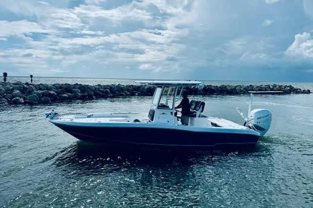 The Image of 2021 Crevalle 26 HCO boat on water near rocky shoreline under cloudy sky. - 0