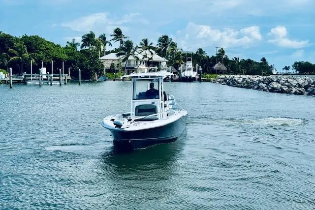 Slide: The Image of 2021 Crevalle 26 HCO boat navigating a scenic coastal waterway with palm trees. - 2