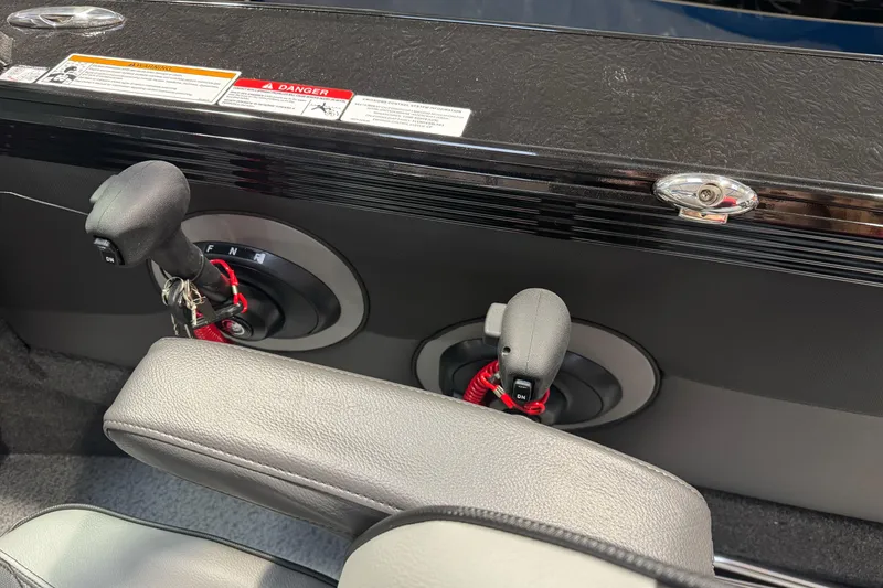 Slide: The Image of Interior controls of a 2026 Lund 1975 Tyee boat, featuring gear levers and warning labels. - 18