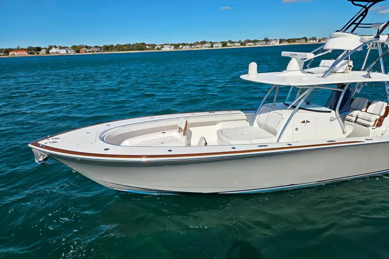 Slide: The Image of 2025 Valhalla Boatworks V-41 cruising on clear blue water near a coastal town. - 2