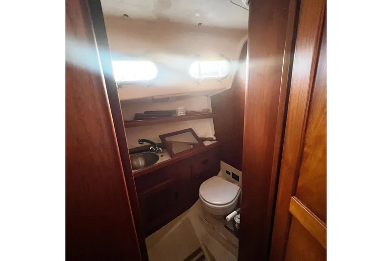 Slide: The Image of 1975 Ranger Yachts 33 interior bathroom with wooden cabinetry and porthole windows. - 5