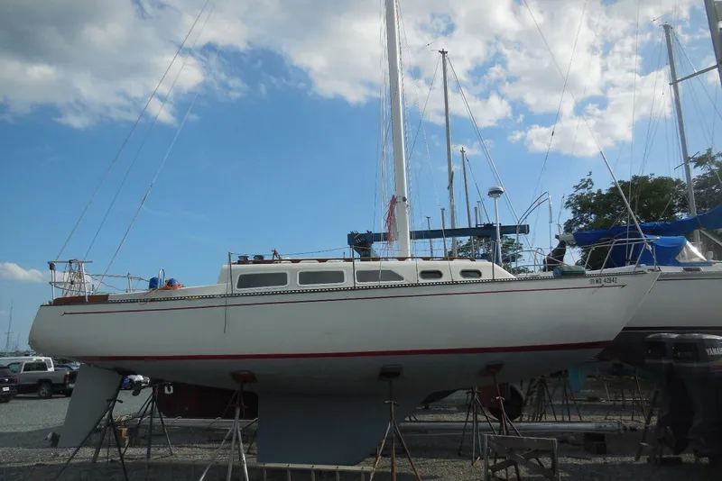 The Image of 1975 Ranger Yachts 33 sailboat on dry dock under a partly cloudy sky. - 0