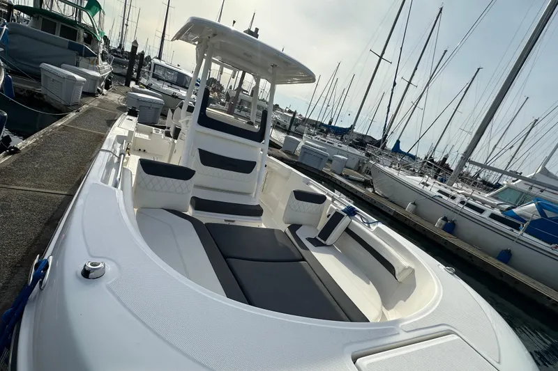 Slide: The Image of 2023 Bayliner Trophy T24CC boat docked at a marina, surrounded by sailboats. - 14