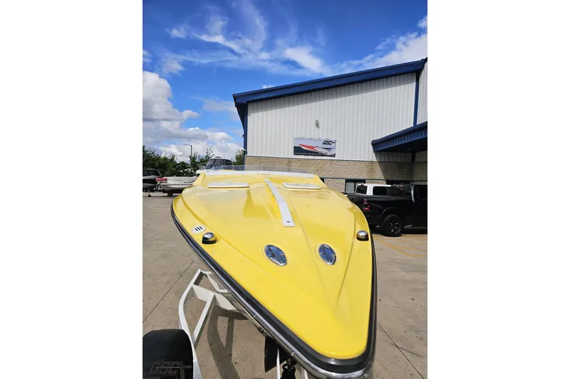 Slide: The Image of 2007 Baja 26 Outlaw speedboat in vibrant yellow, parked outdoors under a blue sky. - 16