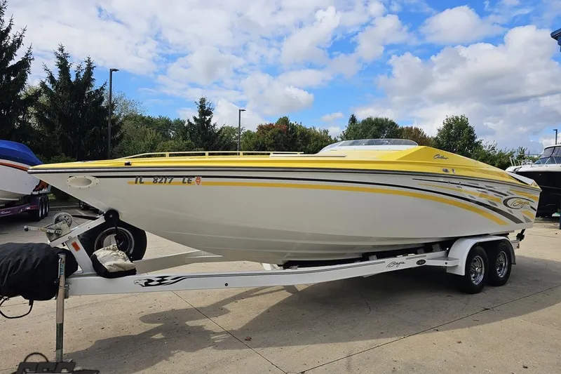 Slide: The Image of 2007 Baja 26 Outlaw speedboat with yellow accents on a trailer, parked outdoors. - 19