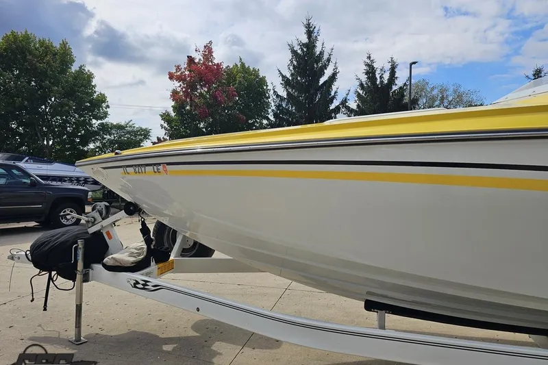 Slide: The Image of 2007 Baja 26 Outlaw boat with yellow accents on a trailer, parked outdoors. - 24