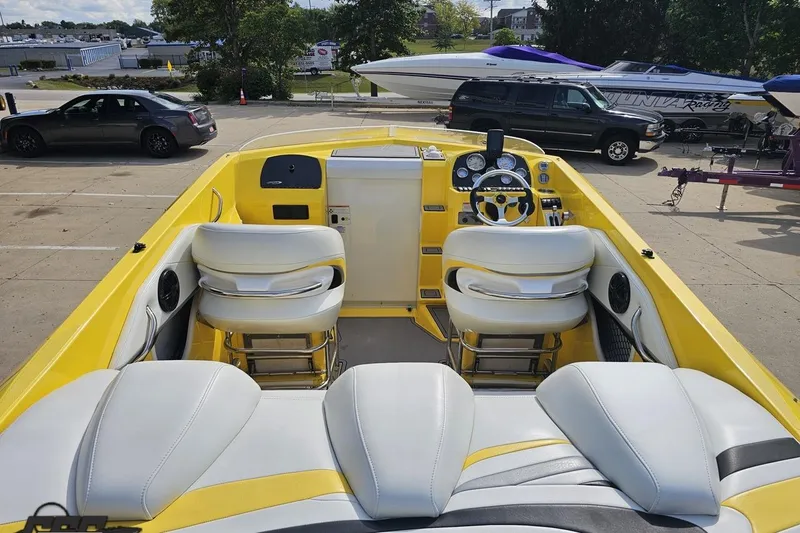Slide: The Image of 2007 Baja 26 Outlaw boat interior with yellow and white seating, parked in a lot. - 46