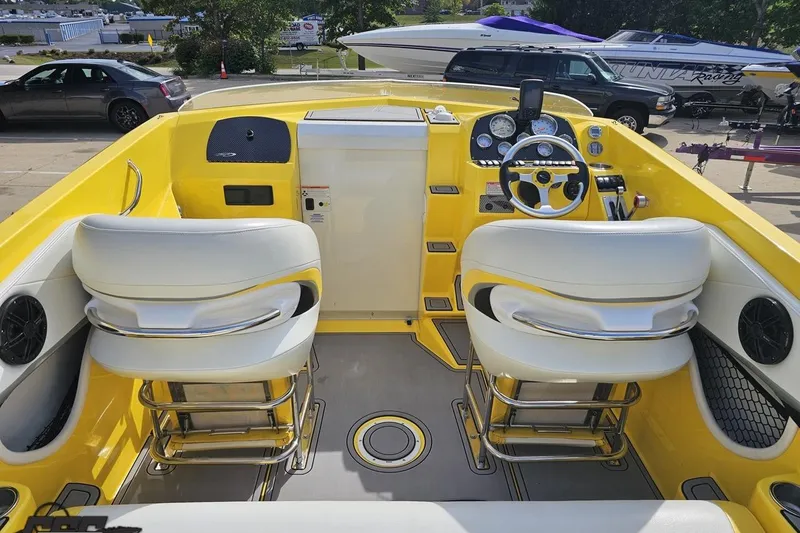 Slide: The Image of 2007 Baja 26 Outlaw boat interior with yellow and white seating, steering wheel, and dashboard. - 49
