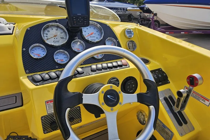 Slide: The Image of 2007 Baja 26 Outlaw boat dashboard with steering wheel and gauges, featuring a vibrant yellow design. - 67