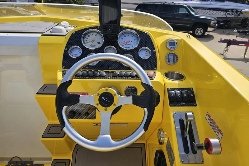 Slide: The Image of 2007 Baja 26 Outlaw boat dashboard with steering wheel and gauges, featuring a vibrant yellow design. - 68