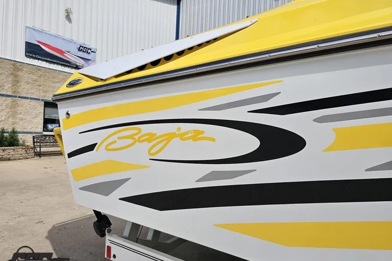 Slide: The Image of Yellow and white 2007 Baja 26 Outlaw boat with bold graphics, parked outside. - 8