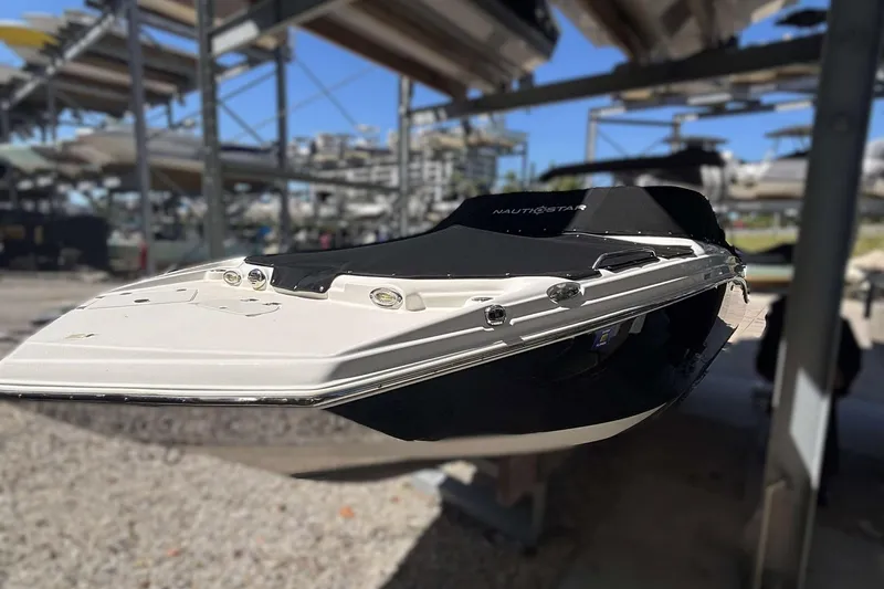 Slide: The Image of 2020 NauticStar 223 DC boat in storage, featuring sleek design and black cover. - 1