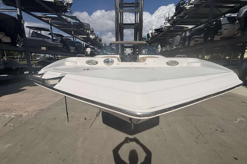 Slide: The Image of 2020 NauticStar 223 DC boat in storage, front view with stacked boats in background. - 11