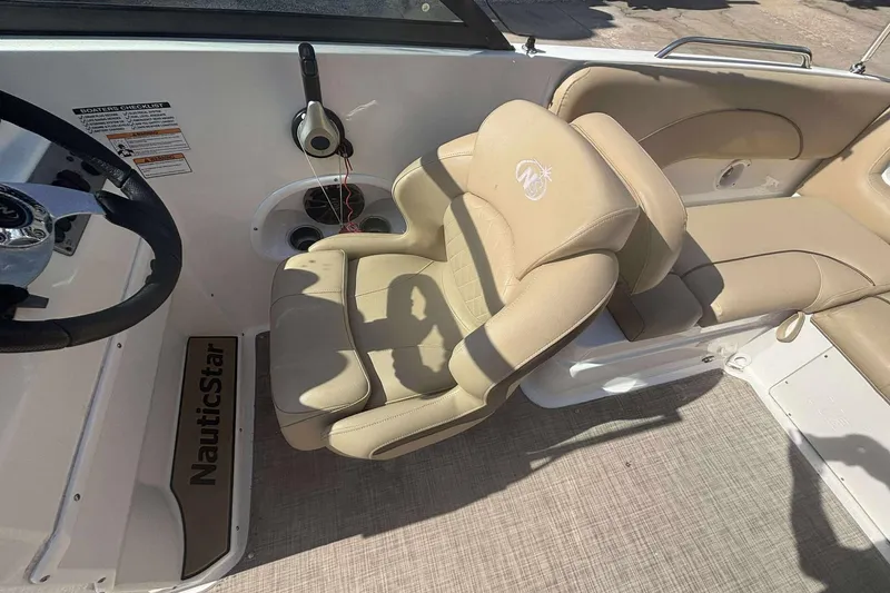 Slide: The Image of 2020 NauticStar 223 DC boat interior with beige seating and steering wheel. - 16