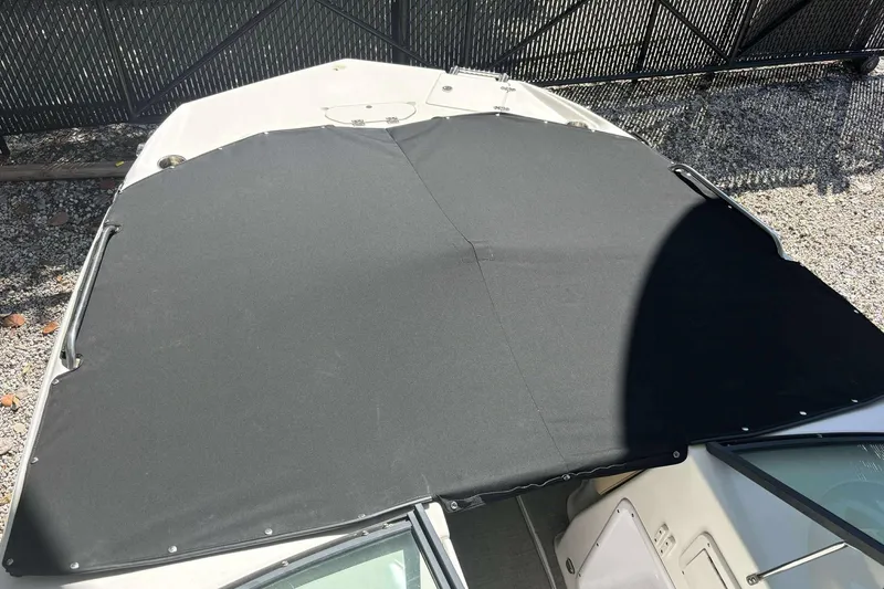 Slide: The Image of 2020 NauticStar 223 DC boat with black cover, parked on gravel. - 4