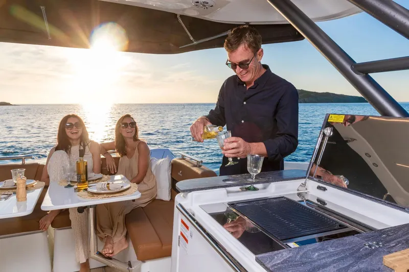 Slide: The Image of Manufacturer Provided Image: Man serving drinks on Four Winns TH38 yacht, 2026, with sunset ocean view. - 6