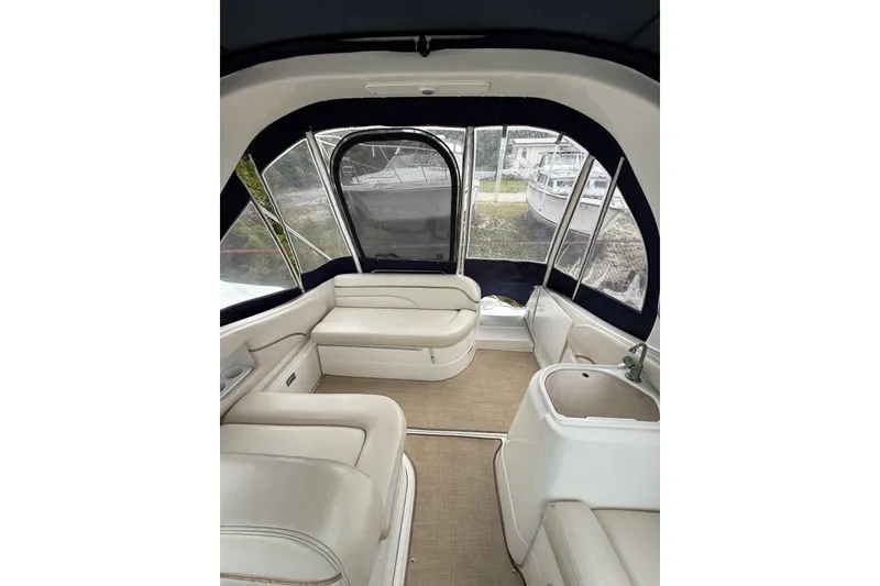 Slide: The Image of 2005 Larson Cabrio 290 boat interior with beige seating and enclosed canopy. - 10