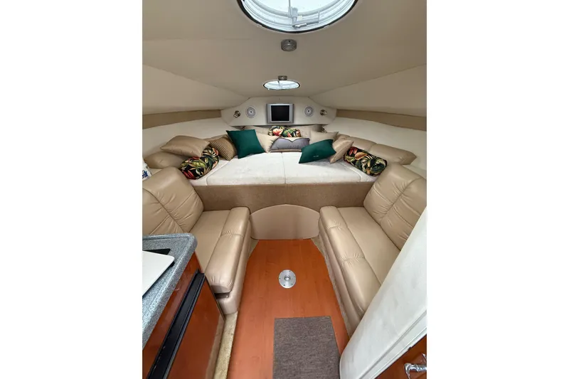 Slide: The Image of 2005 Larson Cabrio 290 cabin interior with beige seating, bed, and decorative pillows. - 18