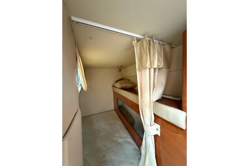 Slide: The Image of 2005 Larson Cabrio 290 interior cabin with cozy sleeping area and curtains. - 22