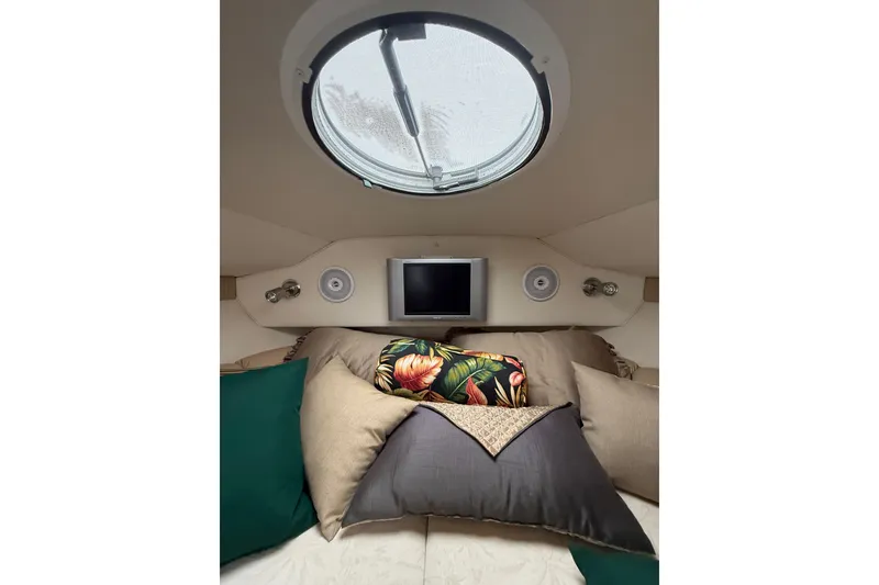 Slide: The Image of 2005 Larson Cabrio 290 cabin interior with pillows, porthole, and small TV. - 24
