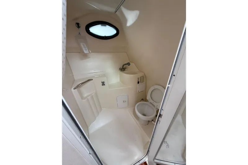 Slide: The Image of 2005 Larson Cabrio 290 boat bathroom with toilet, sink, and porthole window. - 27