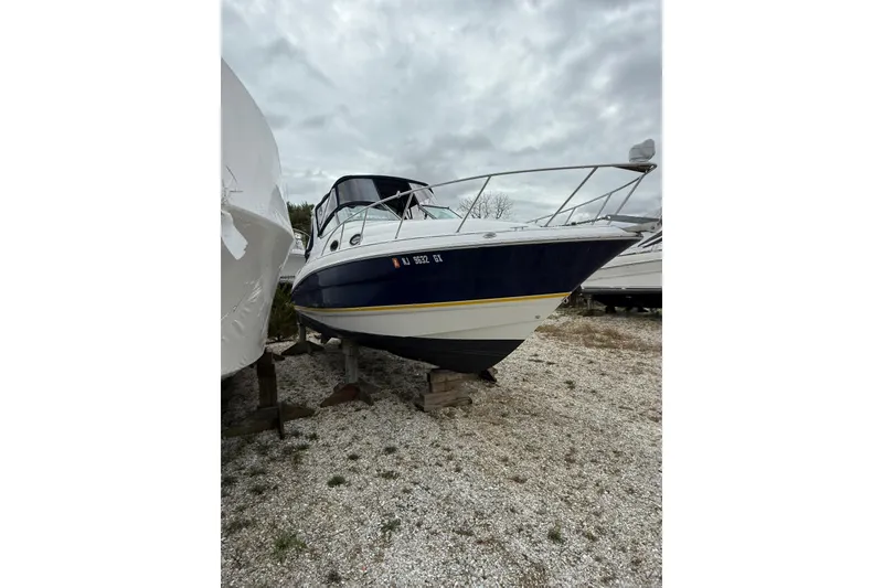 Slide: The Image of 2005 Larson Cabrio 290 boat on gravel, overcast sky background. - 3
