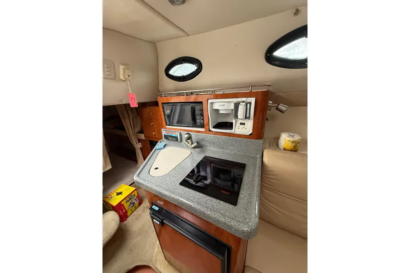 Slide: The Image of 2005 Larson Cabrio 290 boat interior with kitchenette, featuring sink, stove, and microwave. - 31