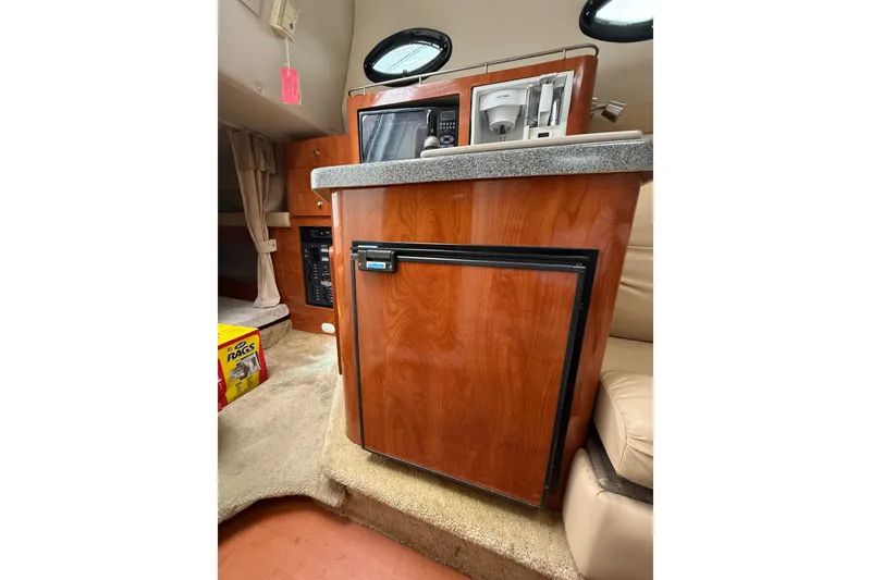 Slide: The Image of 2005 Larson Cabrio 290 cabin interior with kitchenette, featuring wood cabinetry and appliances. - 32