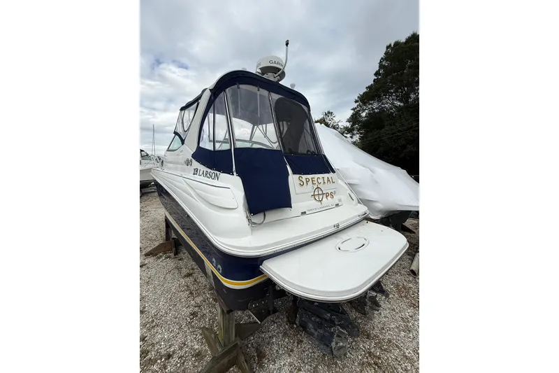 Slide: The Image of 2005 Larson Cabrio 290 boat with blue canopy, parked on gravel. - 4