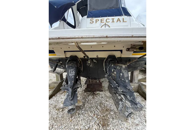 Slide: The Image of 2005 Larson Cabrio 290 boat stern with dual outboard motors on gravel. - 6