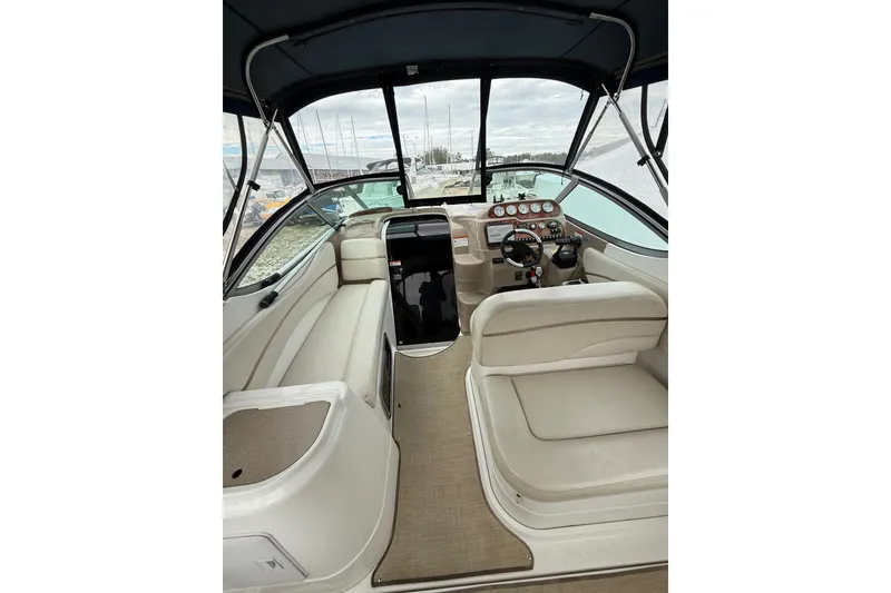 Slide: The Image of 2005 Larson Cabrio 290 boat interior with beige seating and dashboard controls. - 9
