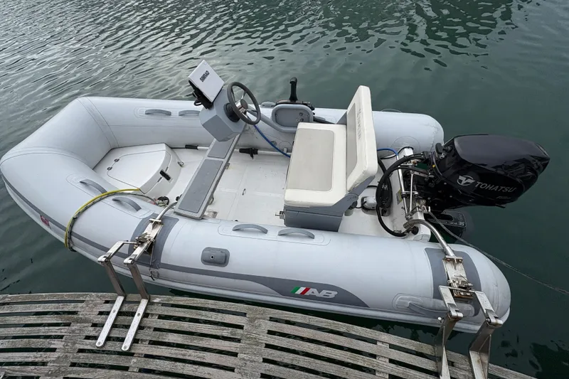 Slide: The Image of Inflatable boat with Tohatsu motor docked on water, near Grand Banks 42 Motoryacht. - 18