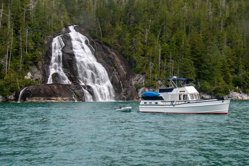 Slide: The Image of Grand Banks 42 Motoryacht (1995) near a scenic waterfall and lush forest backdrop. - 4