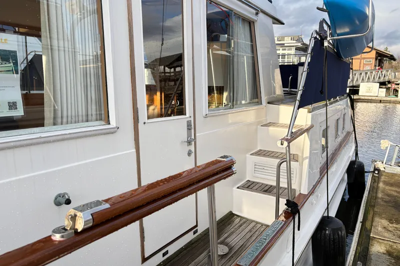 Slide: The Image of 1995 Grand Banks 42 Motoryacht docked, showcasing elegant wooden details and exterior stairs. - 7