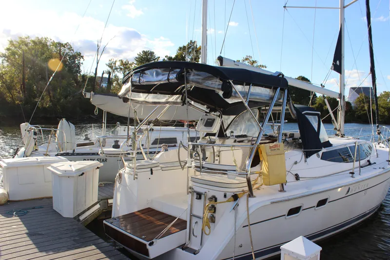 Slide: The Image of 2014 Hunter 33 sailboat docked by a scenic riverside with trees in the background. - 3