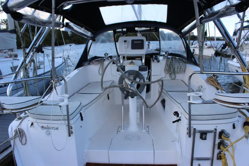 Slide: The Image of 2014 Hunter 33 sailboat cockpit with steering wheel and seating, docked at marina. - 33