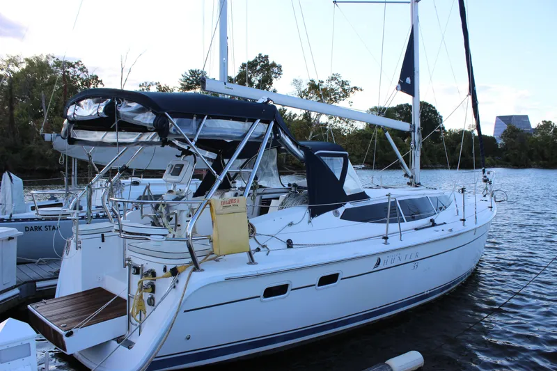 Slide: The Image of 2014 Hunter 33 sailboat docked on a calm river, featuring sleek design and modern amenities. - 34