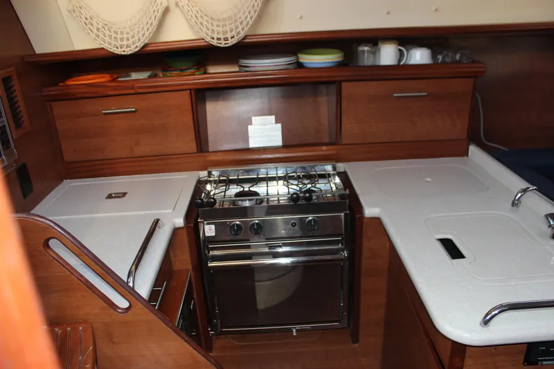 Slide: The Image of Compact kitchen in a 2014 Hunter 33 sailboat with stove, sink, and wooden cabinetry. - 40