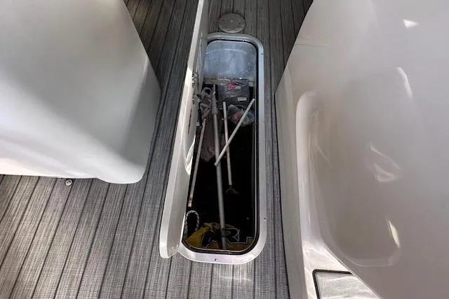 Slide: The Image of 2021 Harris Solstice 230 boat storage compartment with equipment on a striped floor. - 20
