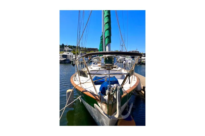 Slide: The Image of 1981 Valiant Cutter sailboat docked at marina, featuring green sail and wooden deck. - 10
